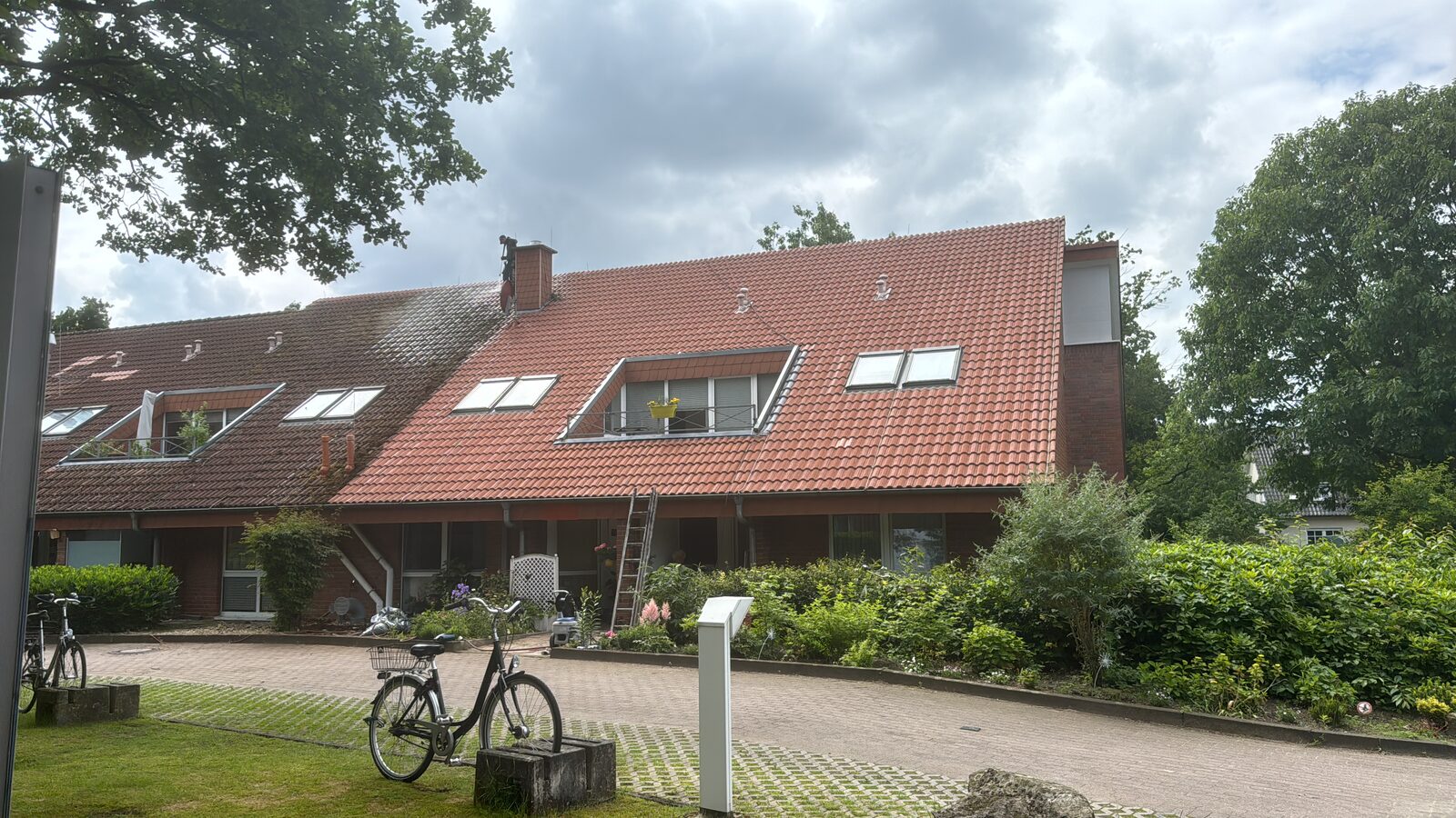 Echtes Projektfoto: links noch unbehandelte Dachfläche, rechts nach der Hochdruckreinigung